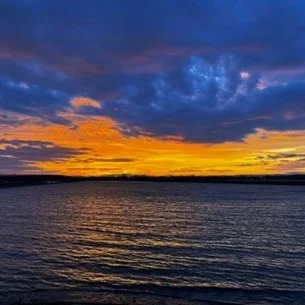 Large blue clouds over an orange sky sunset over lake champlain