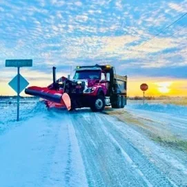 Alburgh town plow truck on snowy road at sunrise